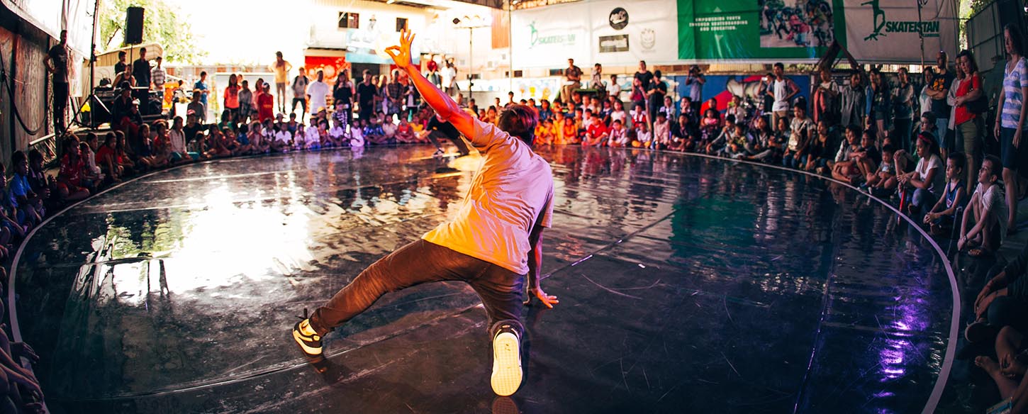 A man is on a stage that is in the round and surrounded by an audience