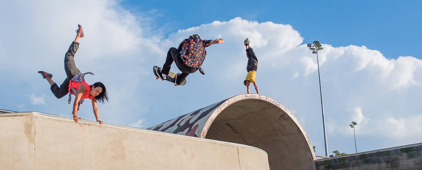 three performers do trickes in a skate park