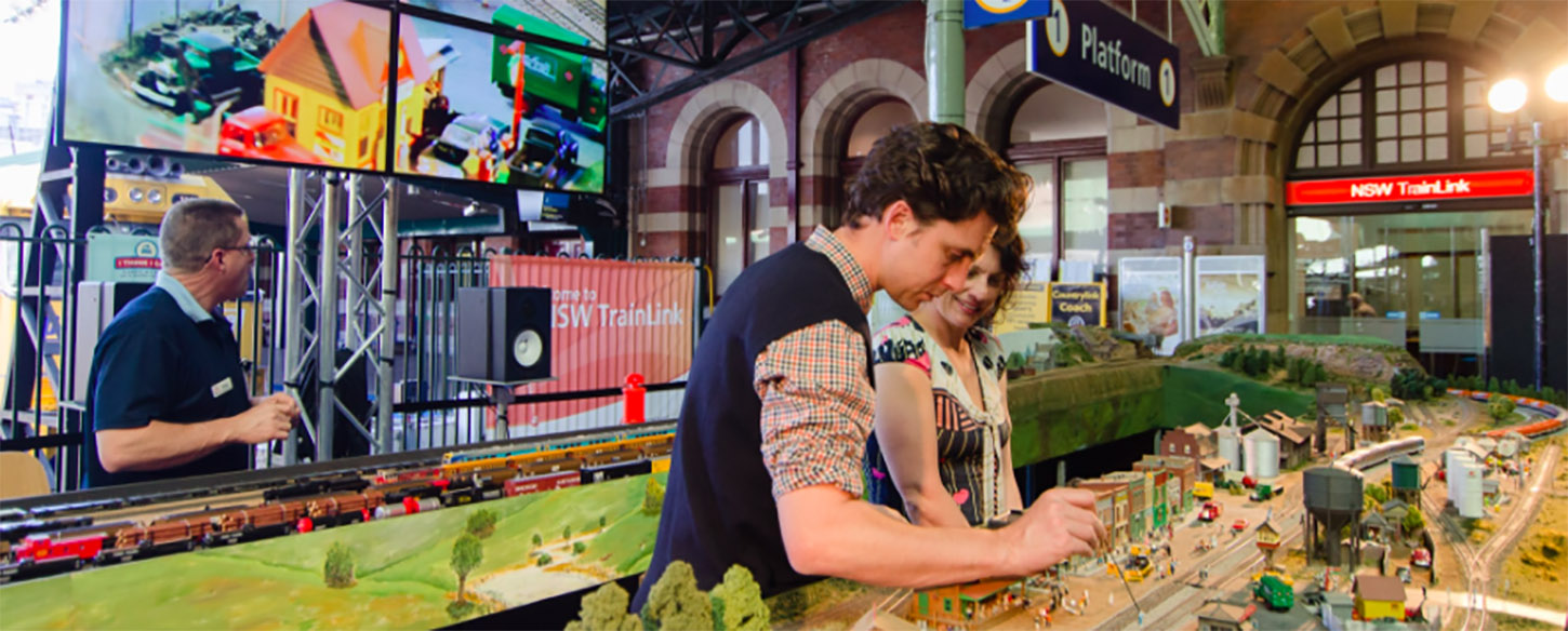 a man and woman put a small piece into the train set