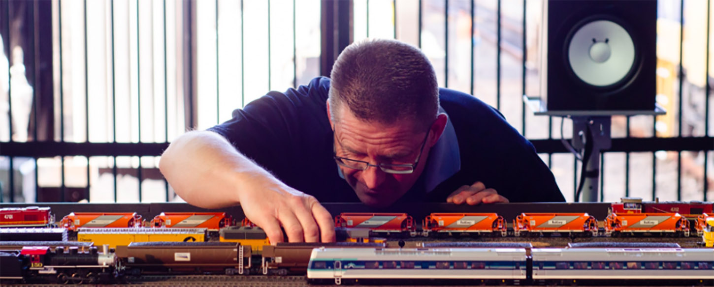 a man looks closely at a toy train